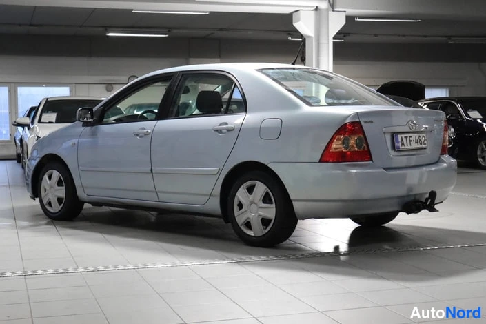 Takaviisto: Vaaleansinisen sedanin takakulmakuu autotallissa, rekisterikilpi.