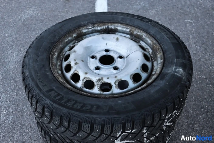 Yksityiskohta: Teräsvellirenkaan nokkareita, Michelin-talvirengas maassa.