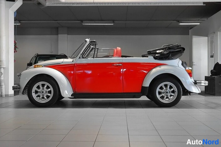 Sivulta: Volkswagen Kupla avoauto sivulta kuvattuna, kori punavalkoinen, kangaskatto auki taitettuna takana.