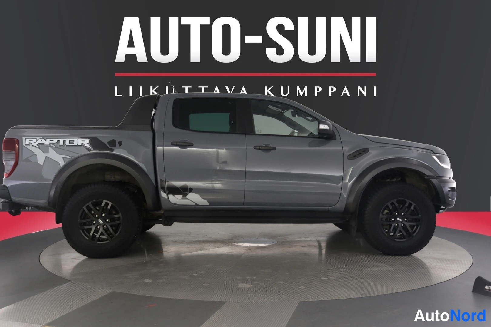 Sivulta: Harmaa Ford Ranger -mallinen avolava-auto, sivunäkymä kuvan vasemmasta reunasta.