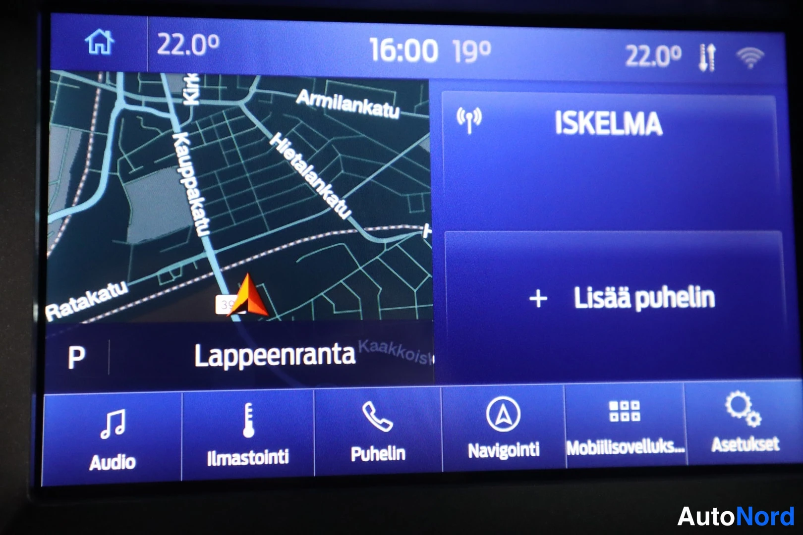 Muu: Auton infotainment-näyttö näyttää Lappeenrannan karttaa, ISKELMA-radioasemaa ja Lisää puhelin -valinnan; alavalikossa Audio, Ilmastointi, Puhelin, Navigointi, M