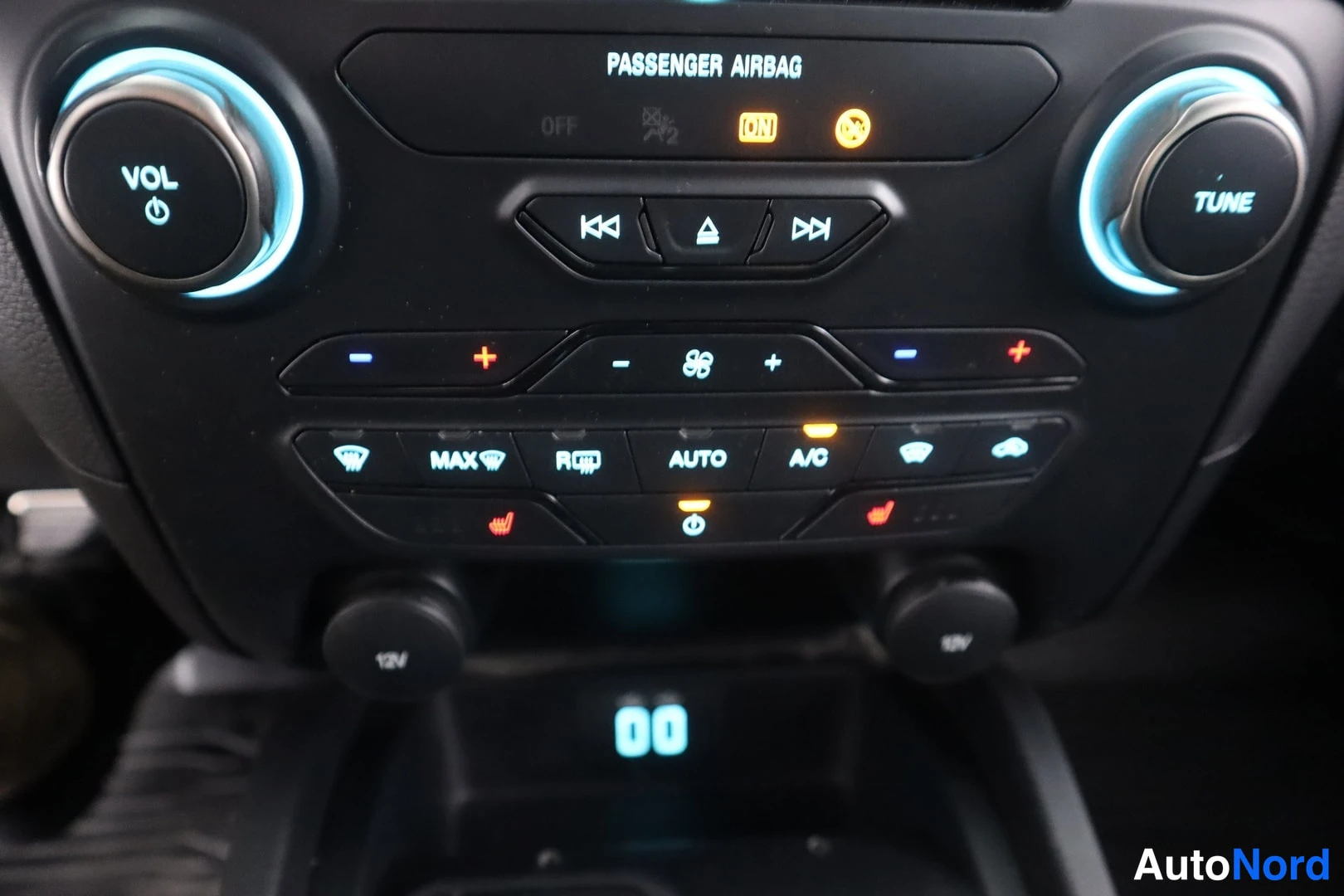 Muu: Auton keskikonsolin näppäimistö: PASSenger AIRBAG -merkintä, VOL- ja TUNE-säätimet, ilmastoinnin painikkeet mm. MAX, AUTO ja A/C sekä kaksi 12V-pistorasiaa.