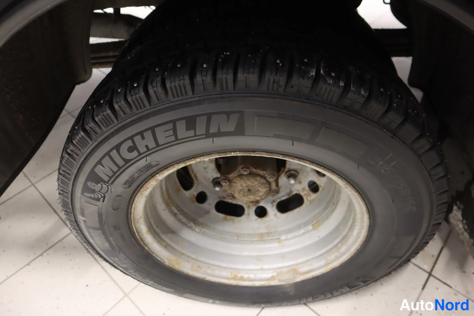 Muu: Lähikuva auton takarenkaasta; Michelin-renkusijainen kitkarengas ja ruostunut teräsvanne.