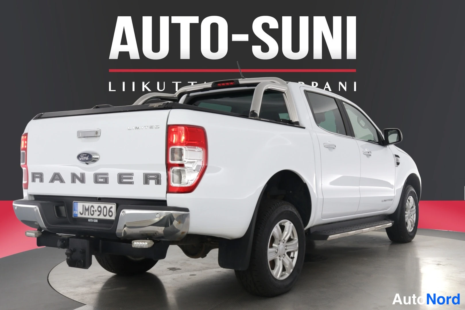 Takaviisto: Valkoinen Ford Ranger -avolava takaa- ja sivulta kuvattuna, taustalla AUTO-SUNI-banneri.