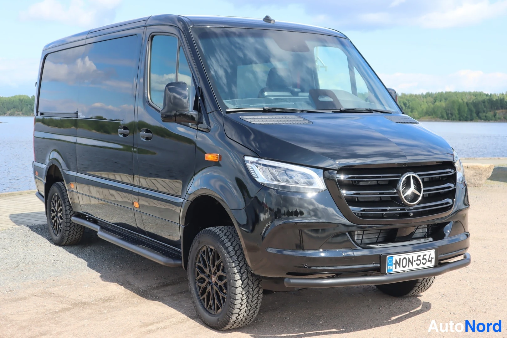 Etuviisto, nokka oikealle: Musta Mercedes-Benz Sprinter -pakettiauto kuvattu etukulmasta oikealta, laidat ja keula näkyvät.