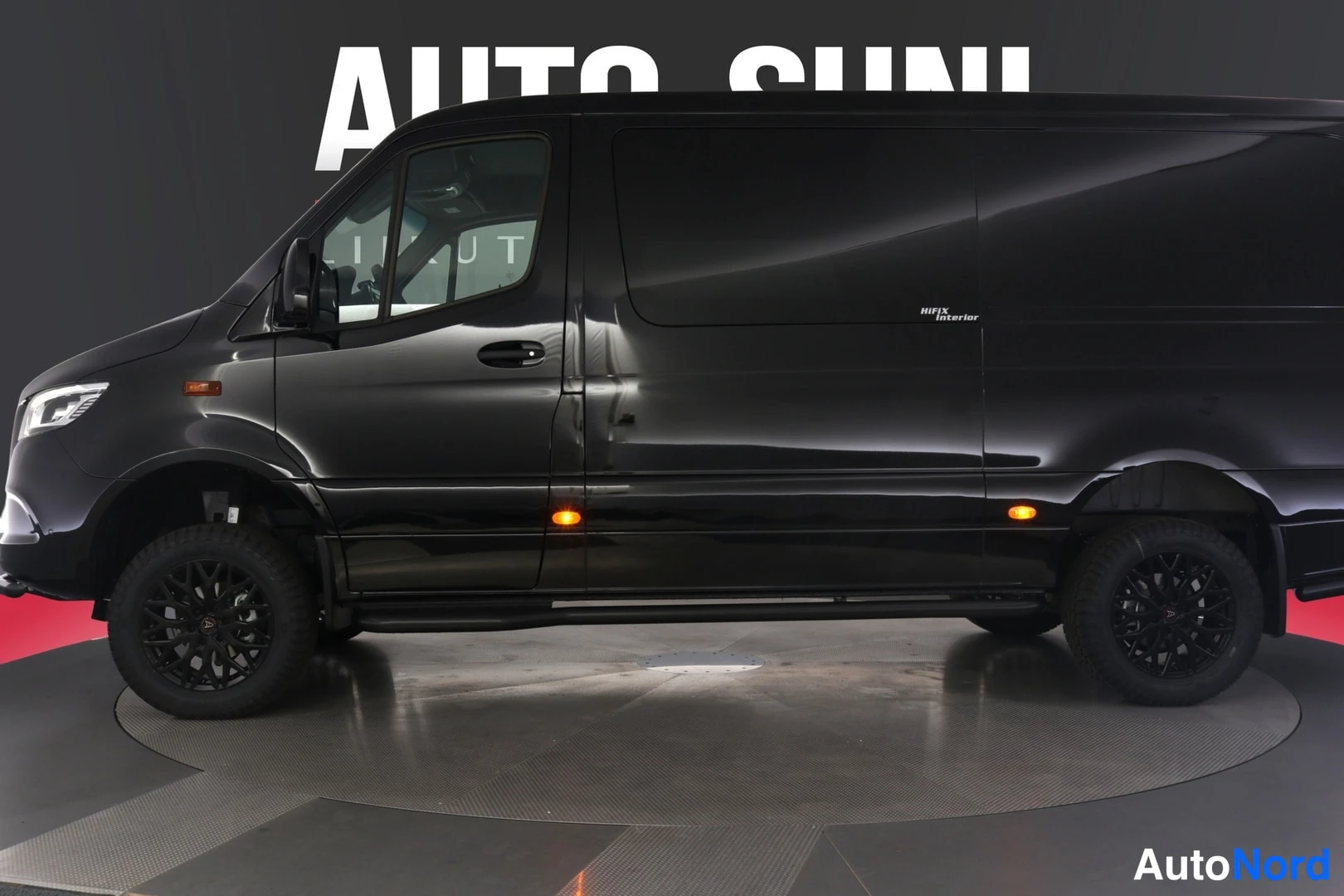 Etuviisto, nokka vasemmalle: Mustan Mercedes-Benz Sprinter -pakettiauton sivukulma, keula vasemmassa reunassa, mustat vanteet ja sivulaitteet.