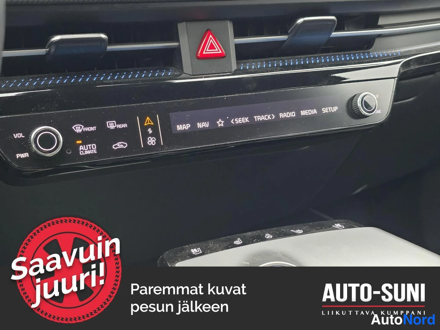 Yksityiskohta: Kojelaudan ilmastointipaneeli, jossa AUTO CLIMATE -merkinnät ja mediakontrollit.