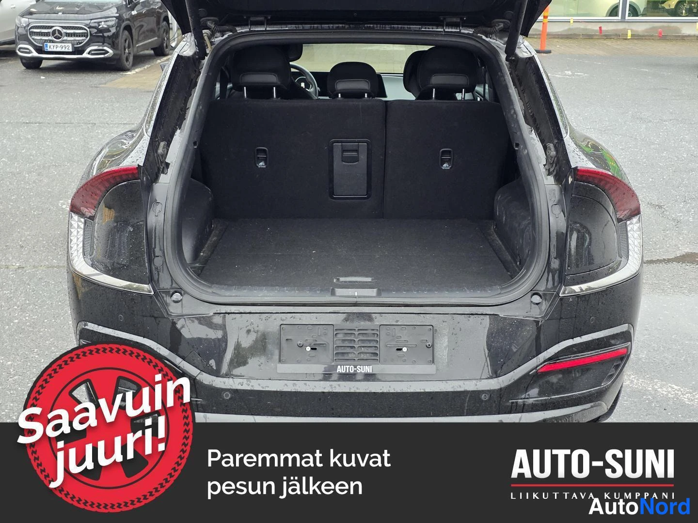 Takaa: Mustan auton takanäkymä avoimella tavaratilalla; takavalojen ääriviivat ja tyhjä, tumma tavaratila näkyvissä.