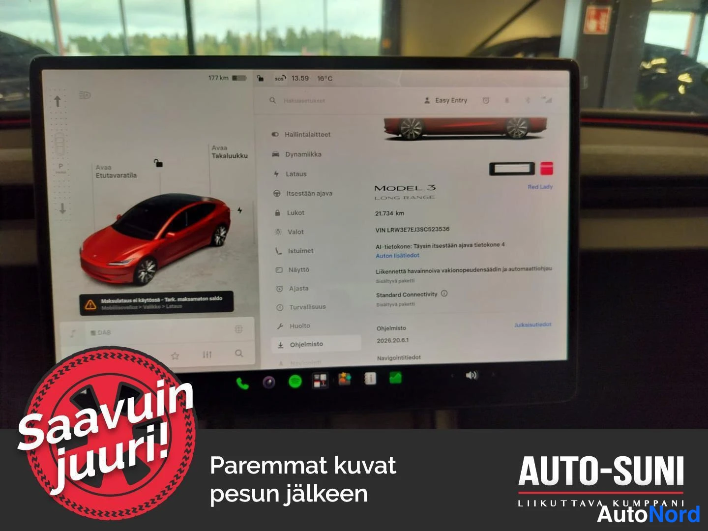 Takaviisto: Tesla Model 3 Long Range -takaa-vinyylikulmassa auto-showroomissa, näkyy taustalla display, joka näyttää auton lisätiedot.