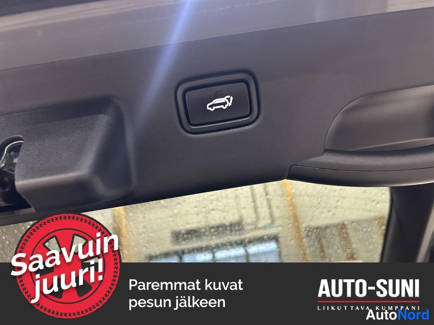 Yksityiskohta: Takaluukun sisäpaneelin painike, jossa auton ja avoimen luukun kuvake, lähikuvana.