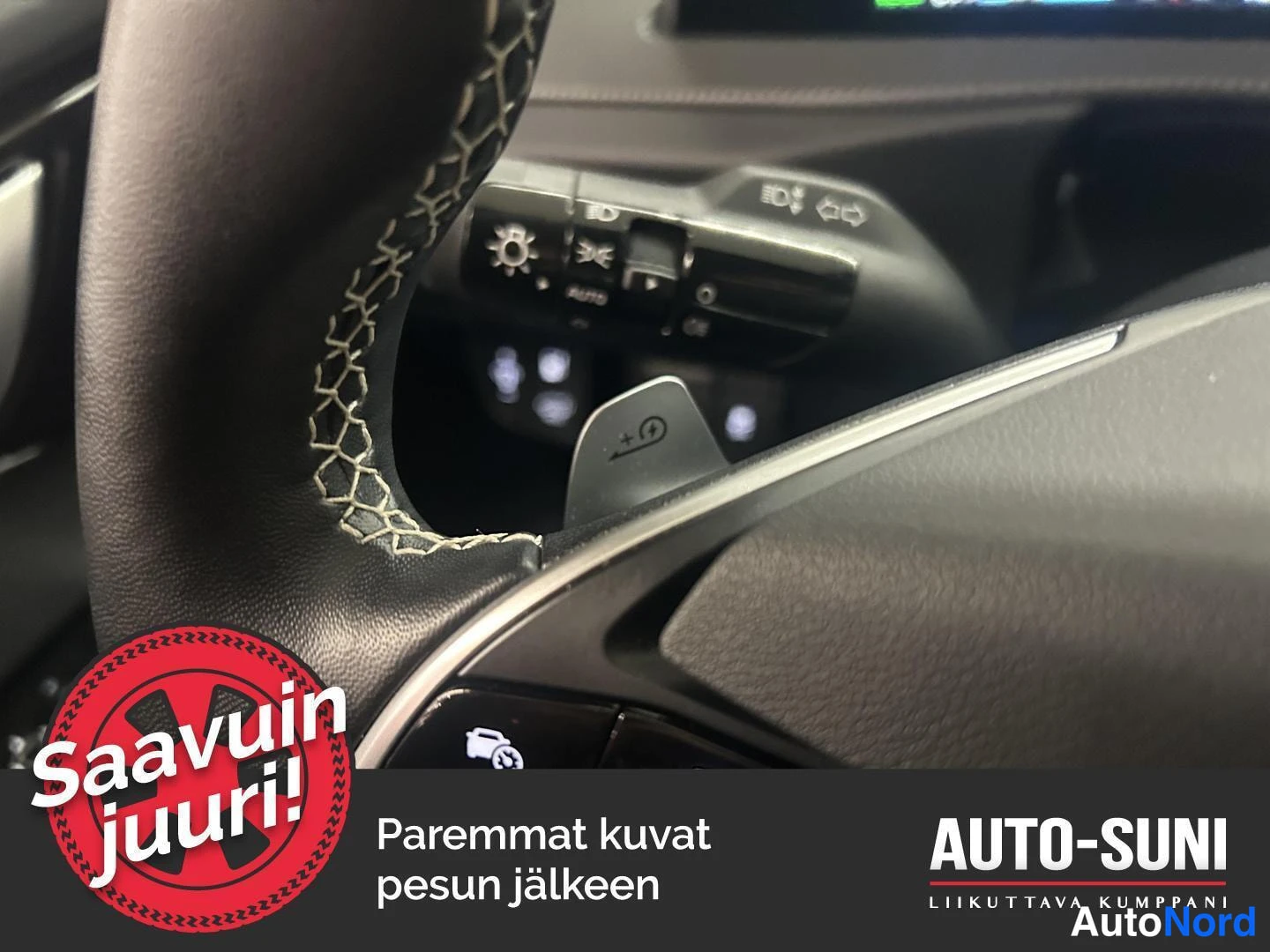 Muu: Ratin takainen +-rattipoljin ja toimintavipu, jonka painikkeissa AUTO- ja nopeudensäätösymbolit; kuvassa myös Auto-Suni-teksti.