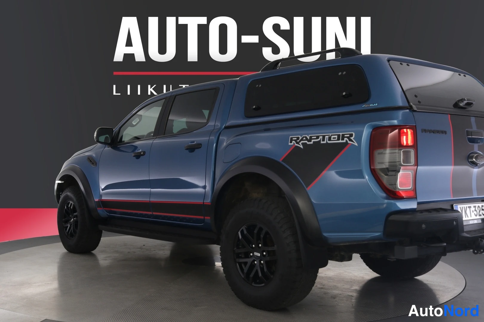 Takaviisto: Sinisen Ford Ranger -lava-auton takapää lähikuvassa, RAPTOR-tarra lavan sivussa, takapuskuri ja rekisterikilpi näkyvät.