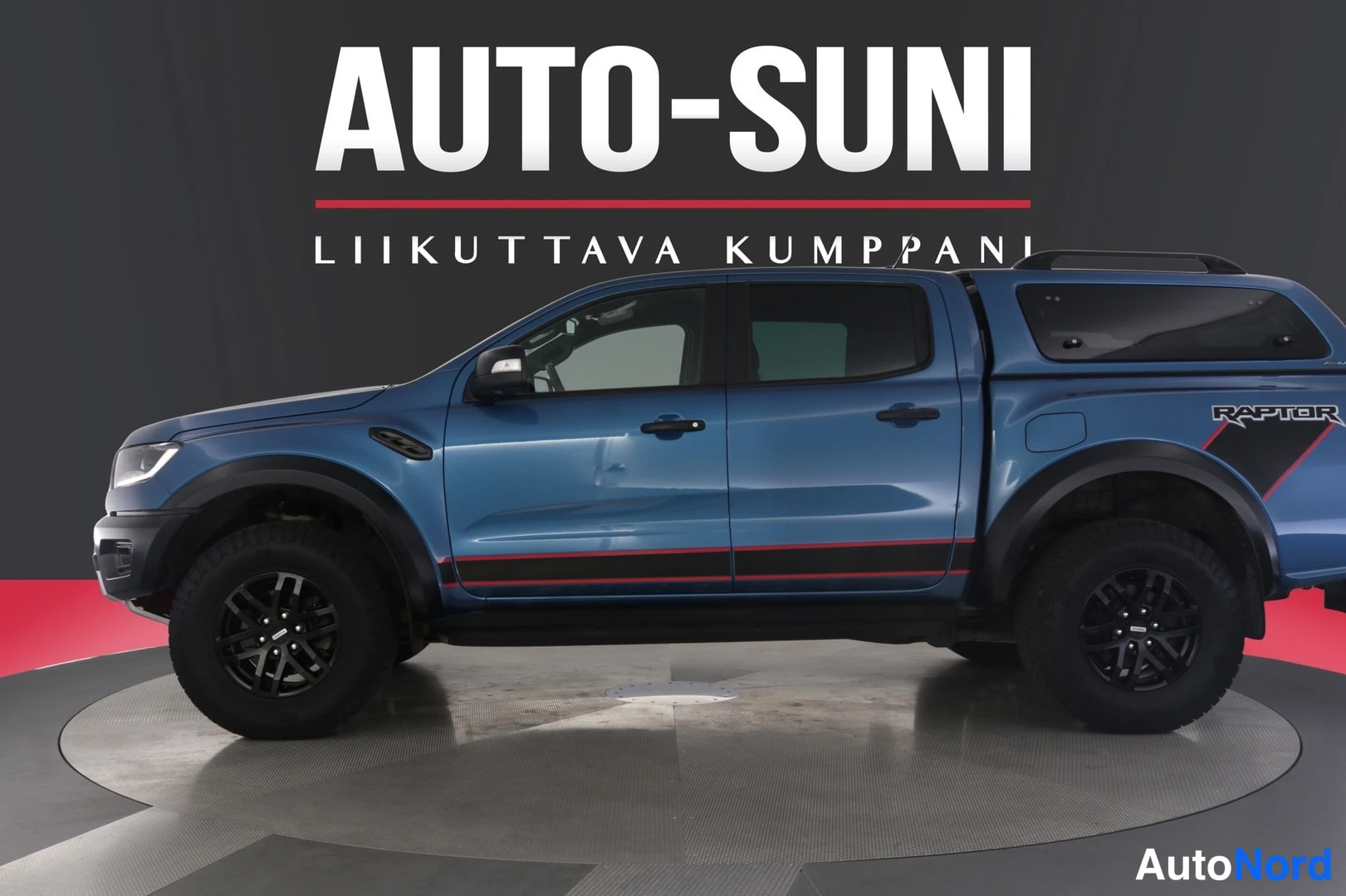 Sivulta: Sivukuva sinisestä Ford Ranger Raptor -pickupista pyörivällä alustalla