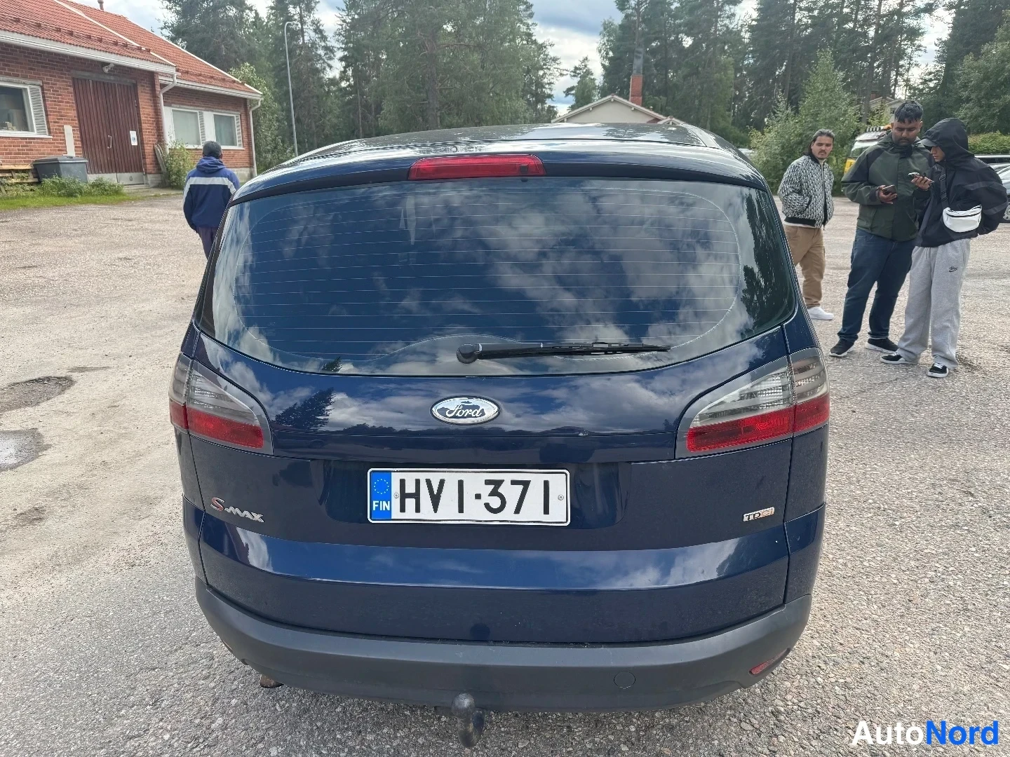 Takaa: Auton takaosa suoraan takaa: tummansininen kori, takaluukussa Ford- ja S-MAX-embleemit sekä TDCi-merkintä, takalasi pyyhkijällä ja lämmitysjohdoilla, rekisterik