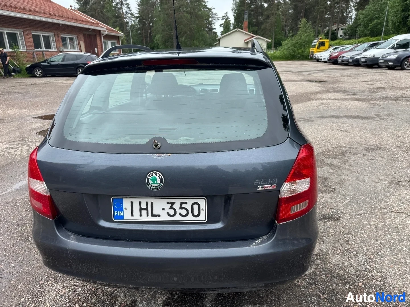 Takaa: Takakuvassa tummanharmaa Skoda Fabia Combi, jonka tunkilla ja pyörillä on rekisterinumero. Tavaratilan ikkuna ja takavalot näkyvät.