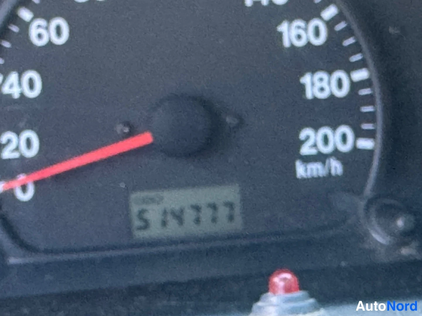 Yksityiskohta: Sumea lähikuva nopeusmittarista, jonka asteikko ulottuu 200 km/h:iin ja nestekidenäytössä lukema.