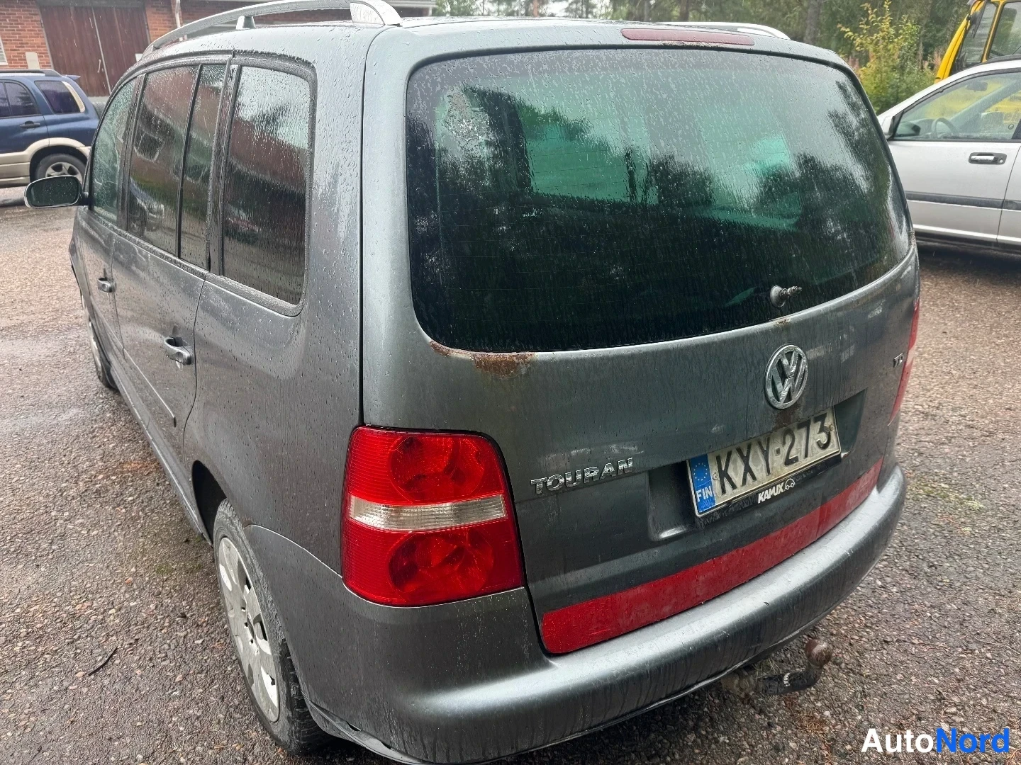 Takaviisto: Takakulmaisku灰 Volkswagen Touranista. Takavaloissa ja takapuskurissa näkyvä ruoste. Vetokoukku puskurin alla.