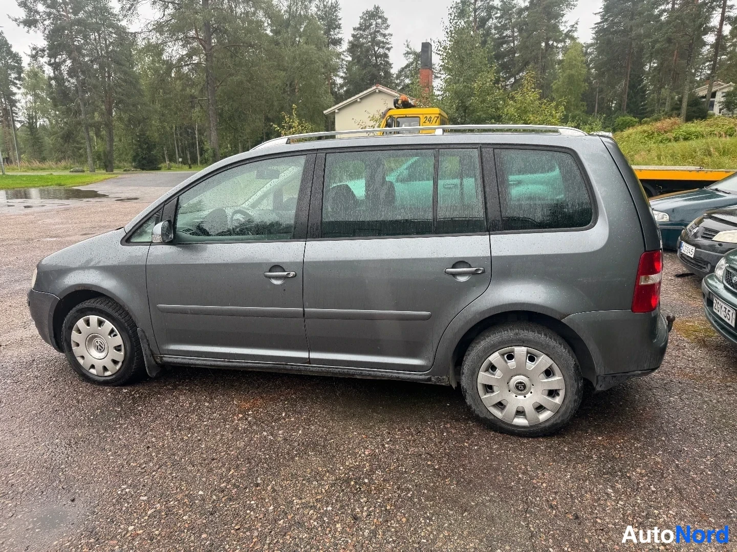 Sivulta: Sivaprofiilu kuvasi koko VW Touranin. Harmaa maalipintainen. Alumiinivanteet kattojärjestelmän kanssa.