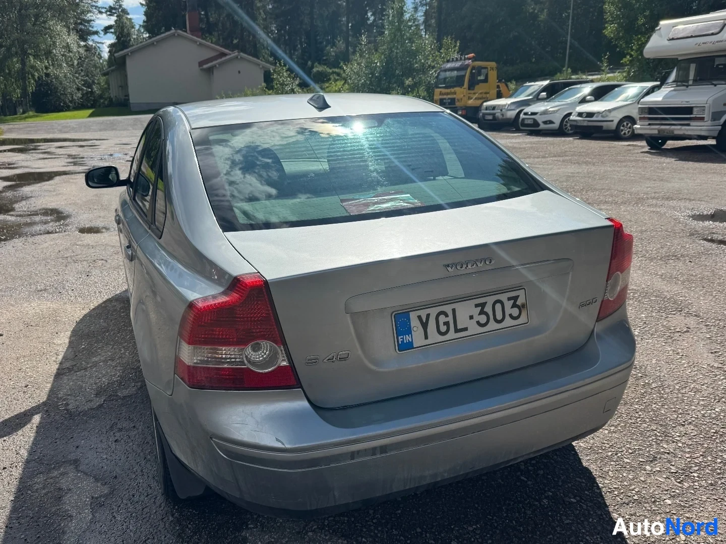 Takaviisto: Takakulma näkyy valkoisessa Volvo S40 -sedanissa. Takavalot ja rekisterikilpi ovat selkeästi nähtävissä.