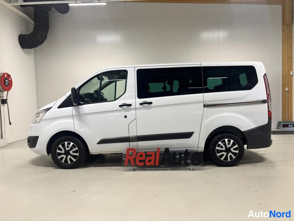 Sivulta: Valkoisen Ford Tourneo Custom -pikkubussin sivuprofiili sisätiloissa.