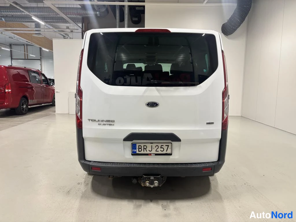 Takaa: Valkoisen Ford Tourneo Customin takaosa, kyltti ja TOURNEO 2.2 TDCI -teksti takaluukussa.