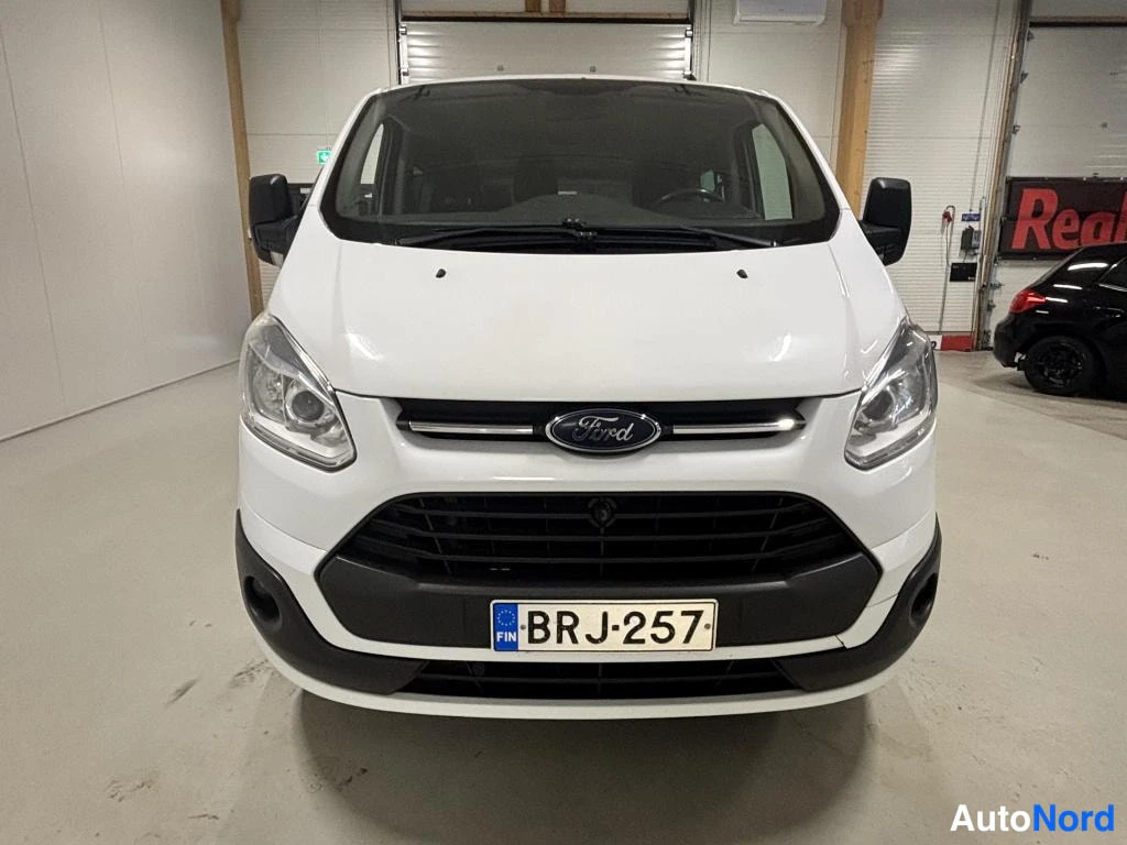 Edestä: Valkoisen pakettiauton etunäkymä, Ford-merkki ja rekisterikilpi näkyvissä.