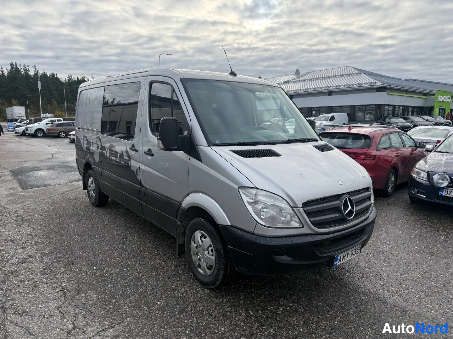 Etuviisto, nokka oikealle: Hopeanharmaa pakettiauto kolmannes­kulmassa edestä oikealta, keulakoru ja oikea sivu näkyvissä.