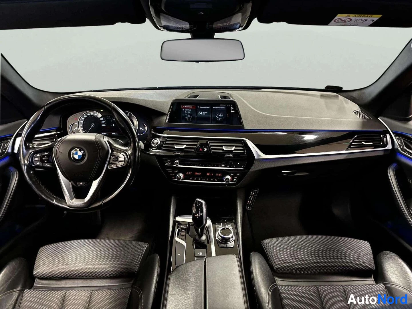 Muu: Suora näkymä kojelautaan: BMW-ohjauspyörä, mittaristo, keskelle sijoitettu näyttö, automaattivaihteiston valitsin ja kaksi etuistuinta.