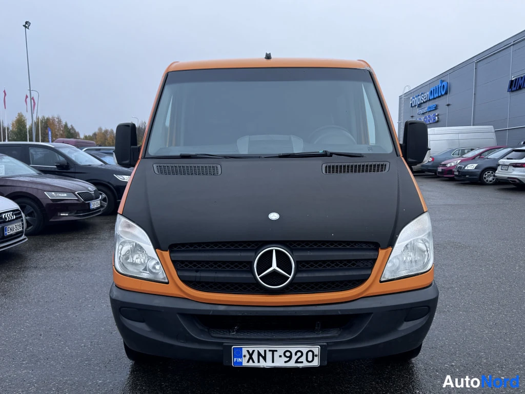 Edestä: Edestä kuvattu oranssi Mercedes-Benz Sprinter, musta huppu ja rekisteri.