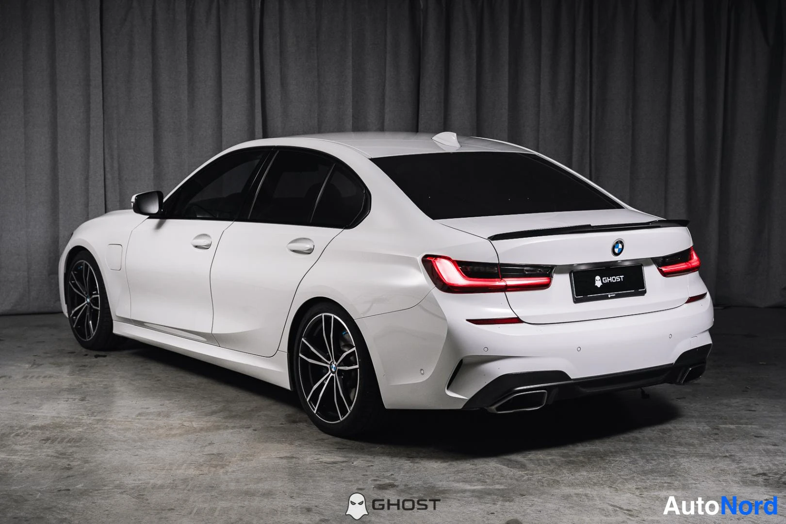Takaviisto: Valkoinen BMW-sedan takaa vasemmalta, takavalot, tummat kevytmetallivanteet.