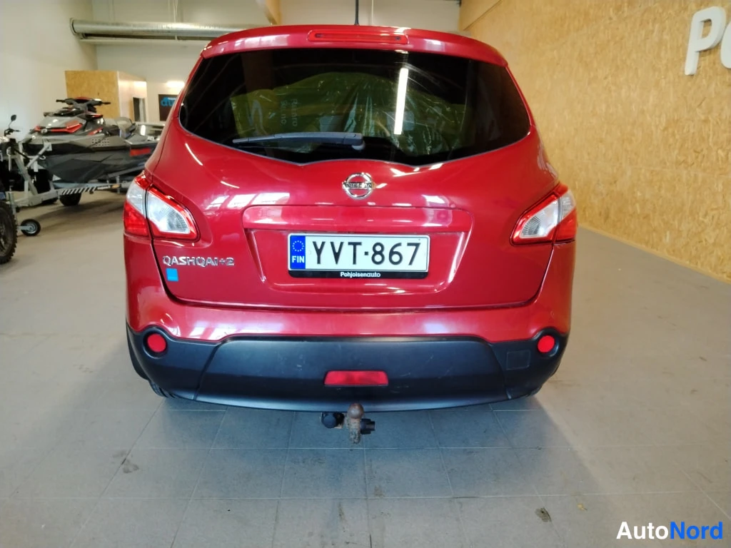 Takaa: Punaisen Nissan Qashqai+2:n takapää suoraan takaa, rekisteri ja hinauskoukku näkyvät.