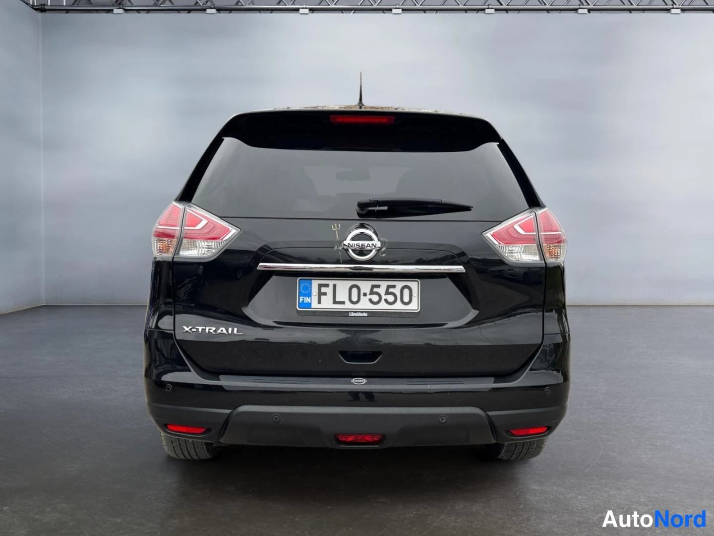 Takaa: Mustan tila-auton takaosa, Nissan-merkki, X-Trail-teksti ja rekisterikilpi FL0-550.
