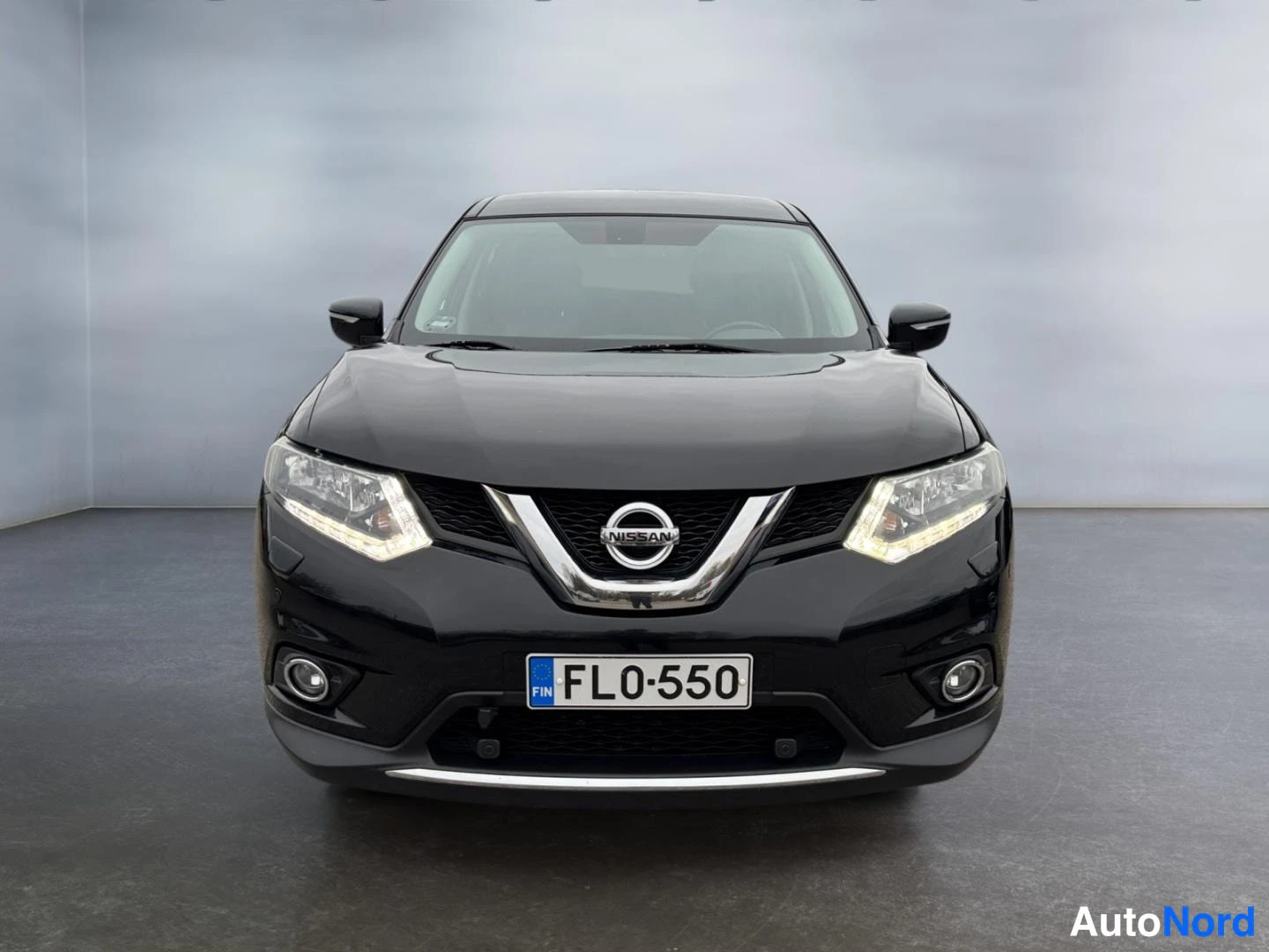 Edestä: Mustan Nissan X-Traden suora etunäkymä, Nissan-merkki etusäleikössä ja rekisteritunnus FL0-550.
