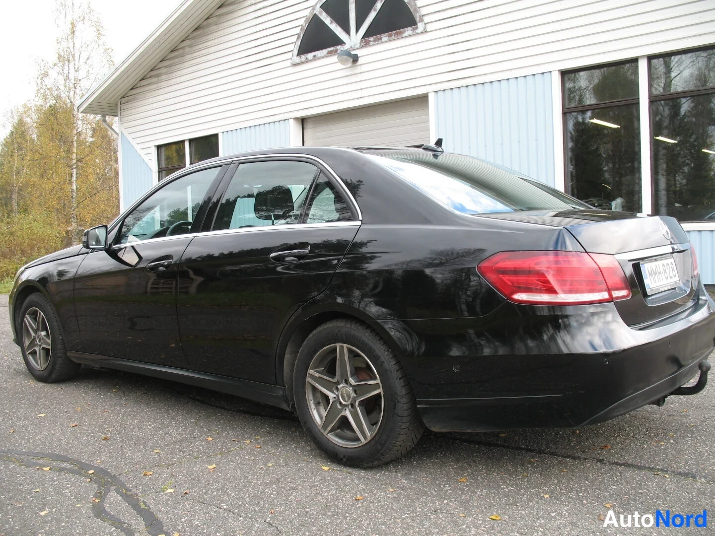 Takaviisto: Musta Mercedes-Benz-sedan takakolmasosakulma, kylki ja takaosa näkyvät, rekisteritunnus.