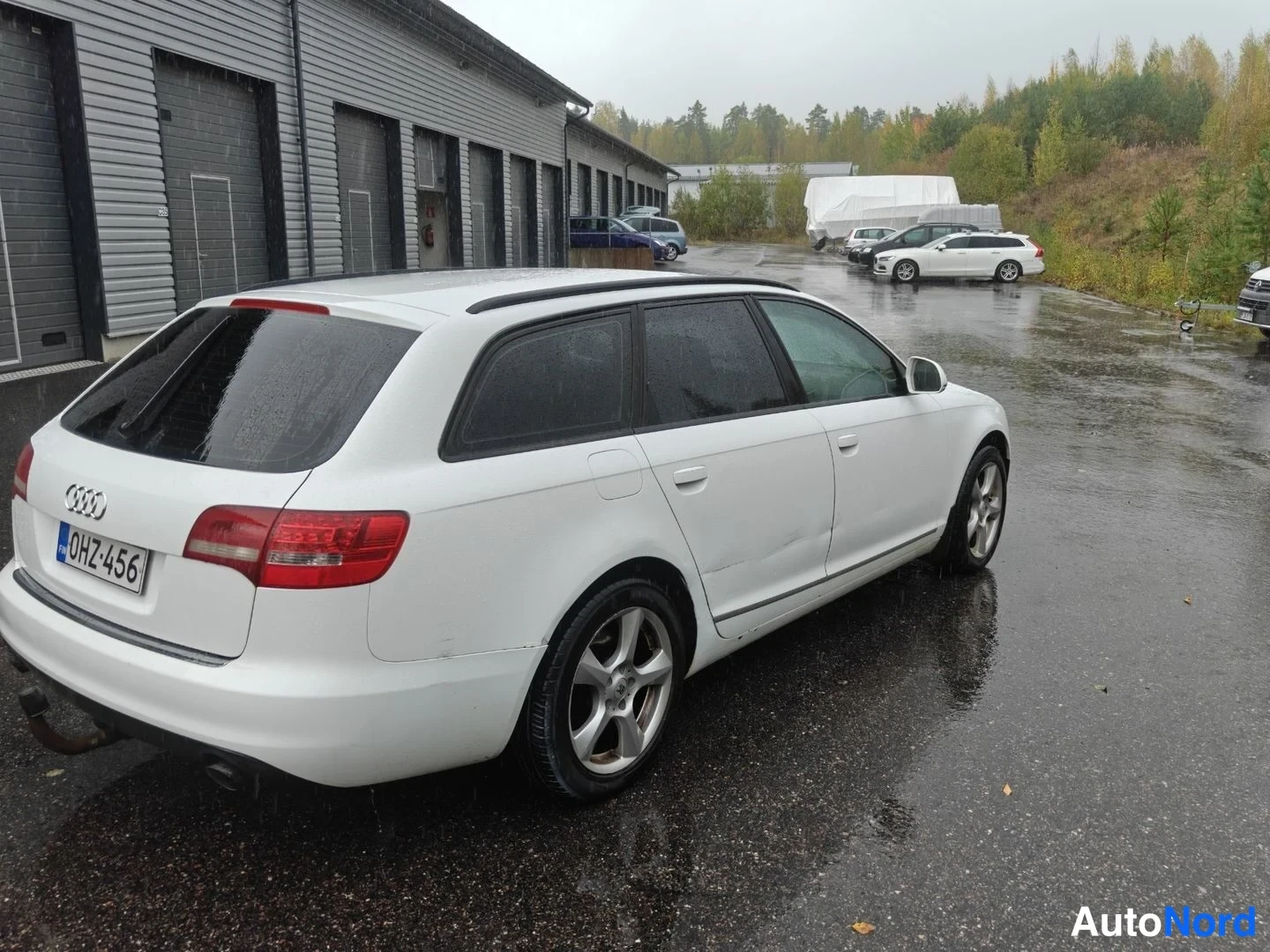 Takaviisto: Valkoinen Audi A6 Avant -farmari takavartinäkymässä takaosasta ja kyljestä, rekisteritunnus.