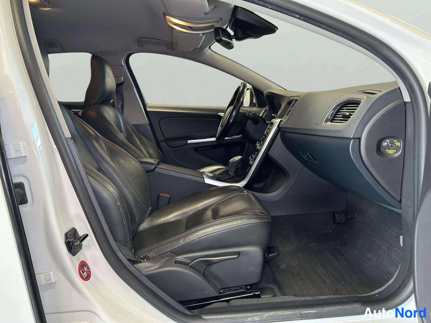 Muu: Volvo V60:n etuistuimet ja ohjaamo avatun oven läpi kuvattuna: mustat nahkaistuimet, ohjauspyörä, keskikonsoli ja suojatyynylapun stoppi myyjän tiedoista.