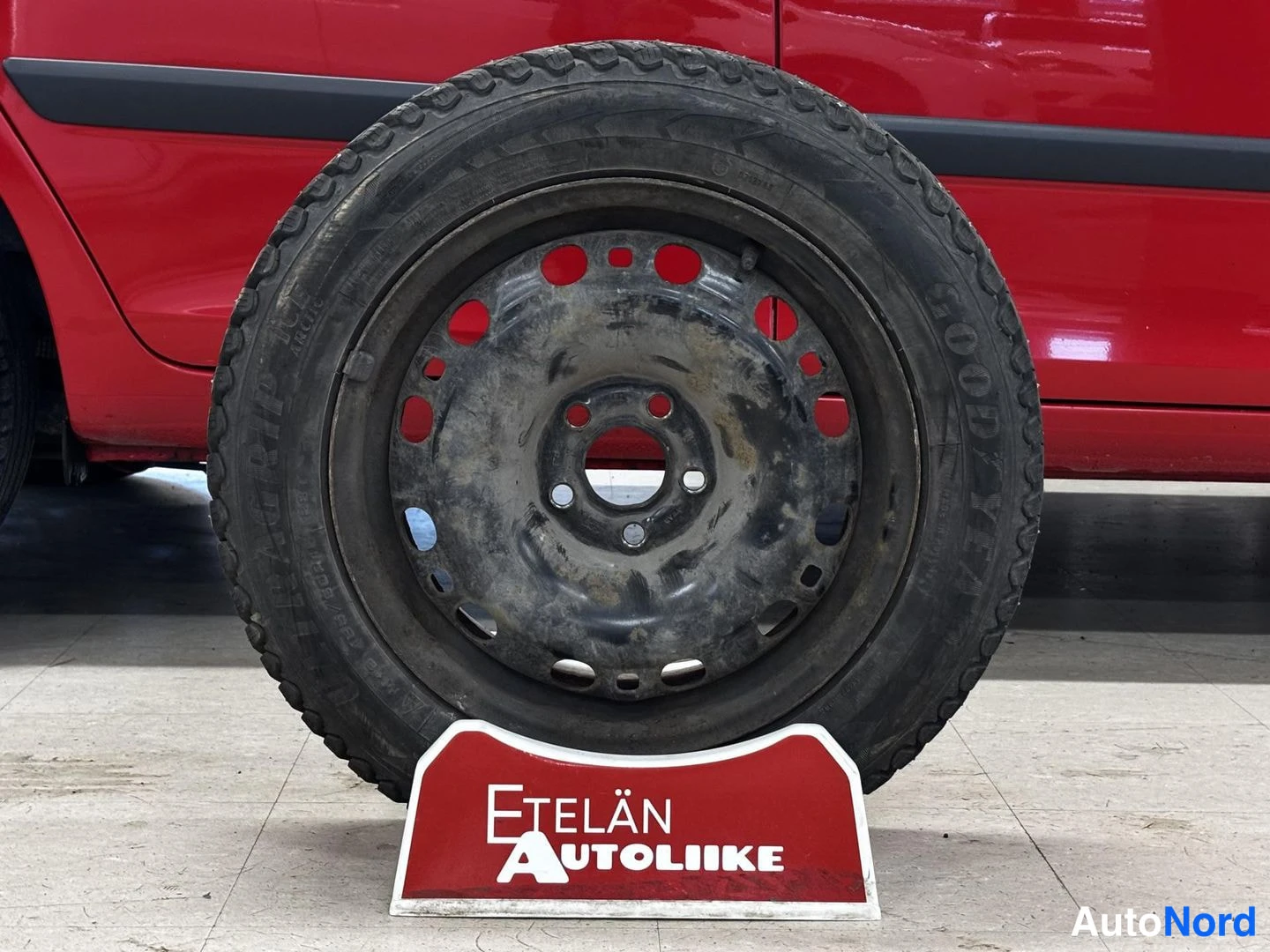Sivulta: Varapyörä Etelän Autoliike-telineessä punaisen auton edessä.