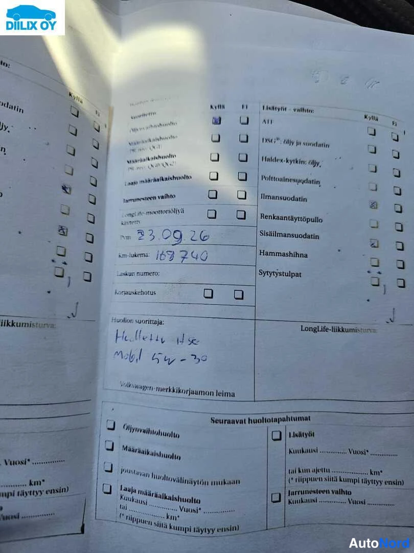 Asiakirja: Close-up photograph of service book page showing handwritten entries dated 23.09.26 with mileage 168740 km, checkmarks in various columns, and printed Finnish t