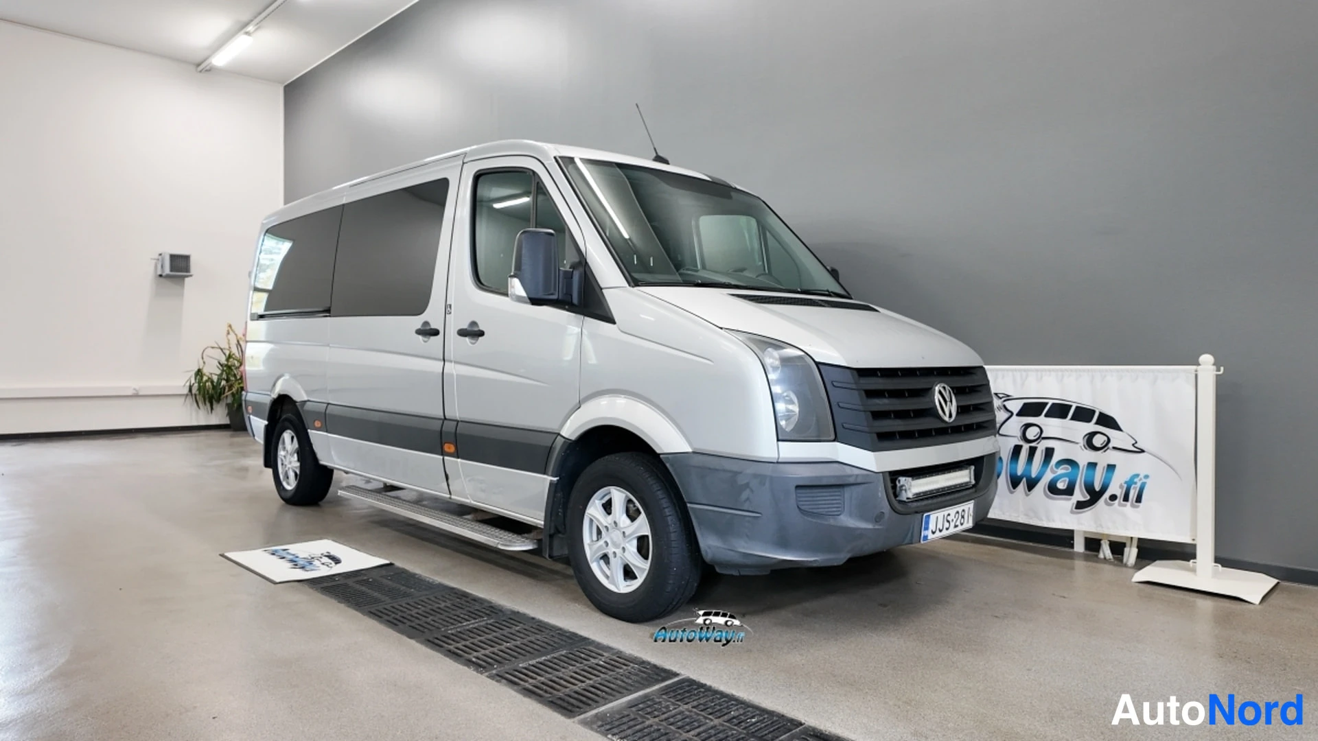 Etuviisto, nokka oikealle: Hopeanvärinen Volkswagen Crafter -pakettiauto etuviistosta oikealta sisätiloissa.