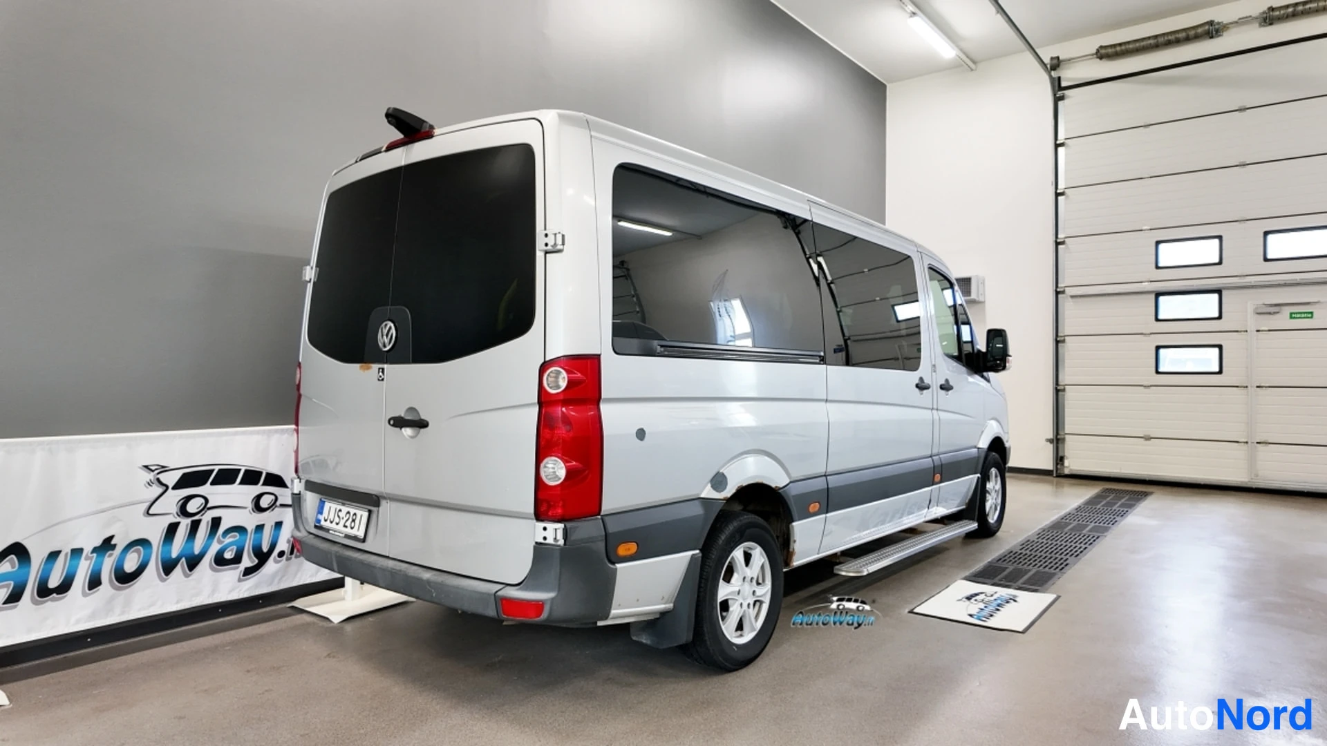 Takaviisto: Hopeanvärinen Volkswagen Crafter -pakettiauto takaviistosta vasemmalta autotallissa.
