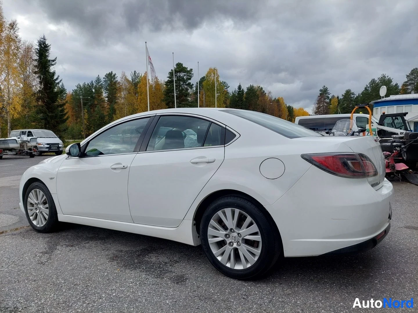 Takaviisto: Valkoinen Mazda 6 -sedan sivulta takaa oikealle; takavalo ja oikeanpuoleinen sivu näkyvissä.