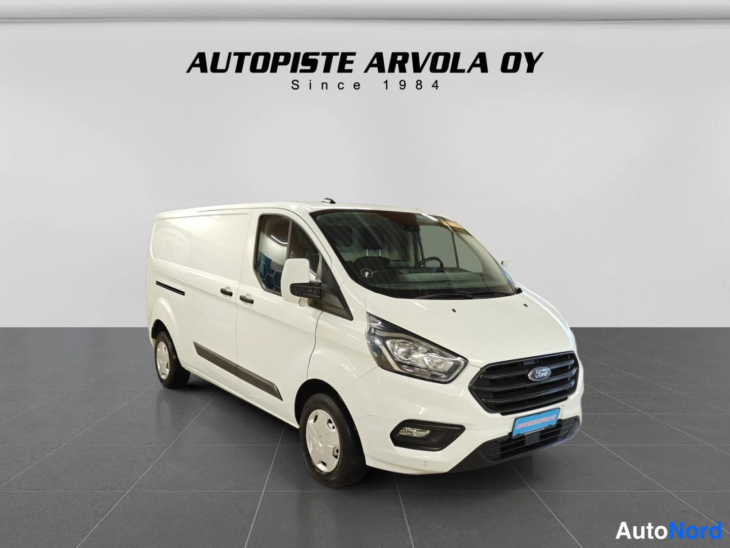Etuviisto, nokka oikealle: Valkoinen Ford Transit Custom -pakettiauto kulmassa kuvattuna etunovalta oikealta, myyjä AUTOPISTE ARVOLA OY.