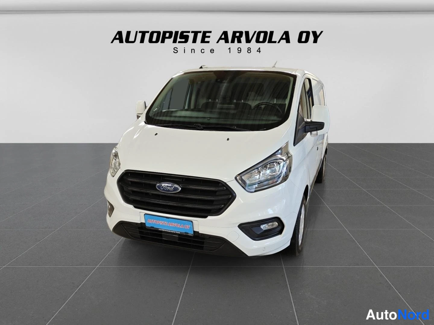 Etuviisto, nokka vasemmalle: Ford Transit Custom edestä, valkoinen koripaneelit
