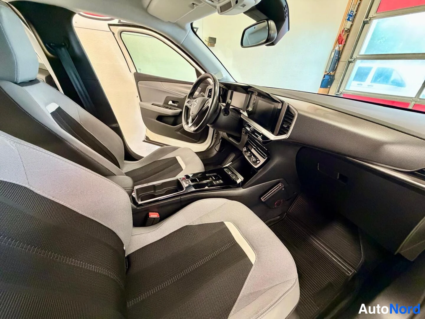 Muu: Opel Mokka - auton sisätilat kuljettajan paikalta katsottuna: kaksivärinen tumma ja harmaa penkki, ohjaustehostin, kosketusnäytöt ja automaattivaihteiston valit