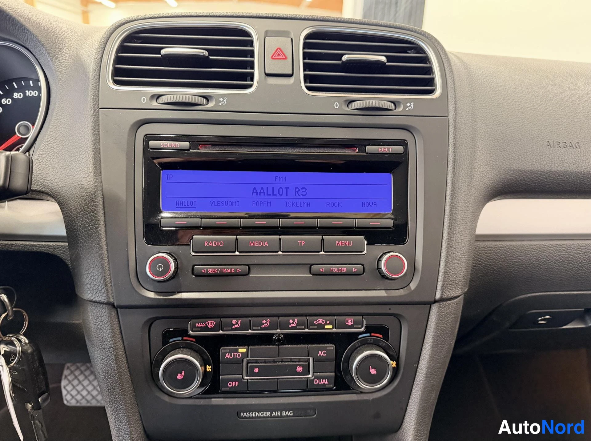 Muu: Keskikonsolin lähikuva: radio näyttää tekstin 'AALLOT R3' ja painikkeet RADIO, MEDIA, TP, MENU, alla kaksivyöhykeilmastoinnin säätimet AUTO, AC, OFF ja DUAL -me