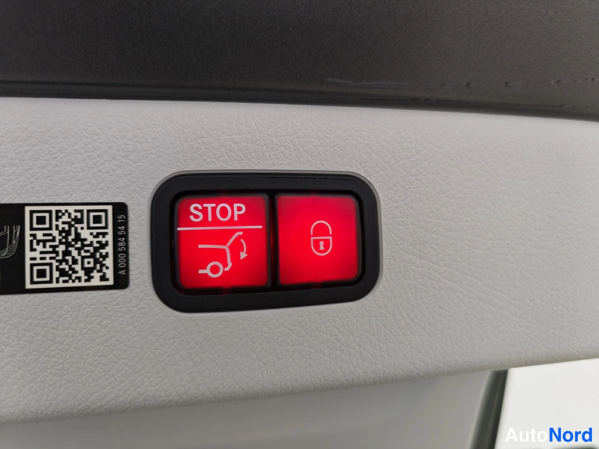 Muu: Punaiset STOP- ja lukitse-napit kannen avaamiseen, vieressä QR-kooditarra.
