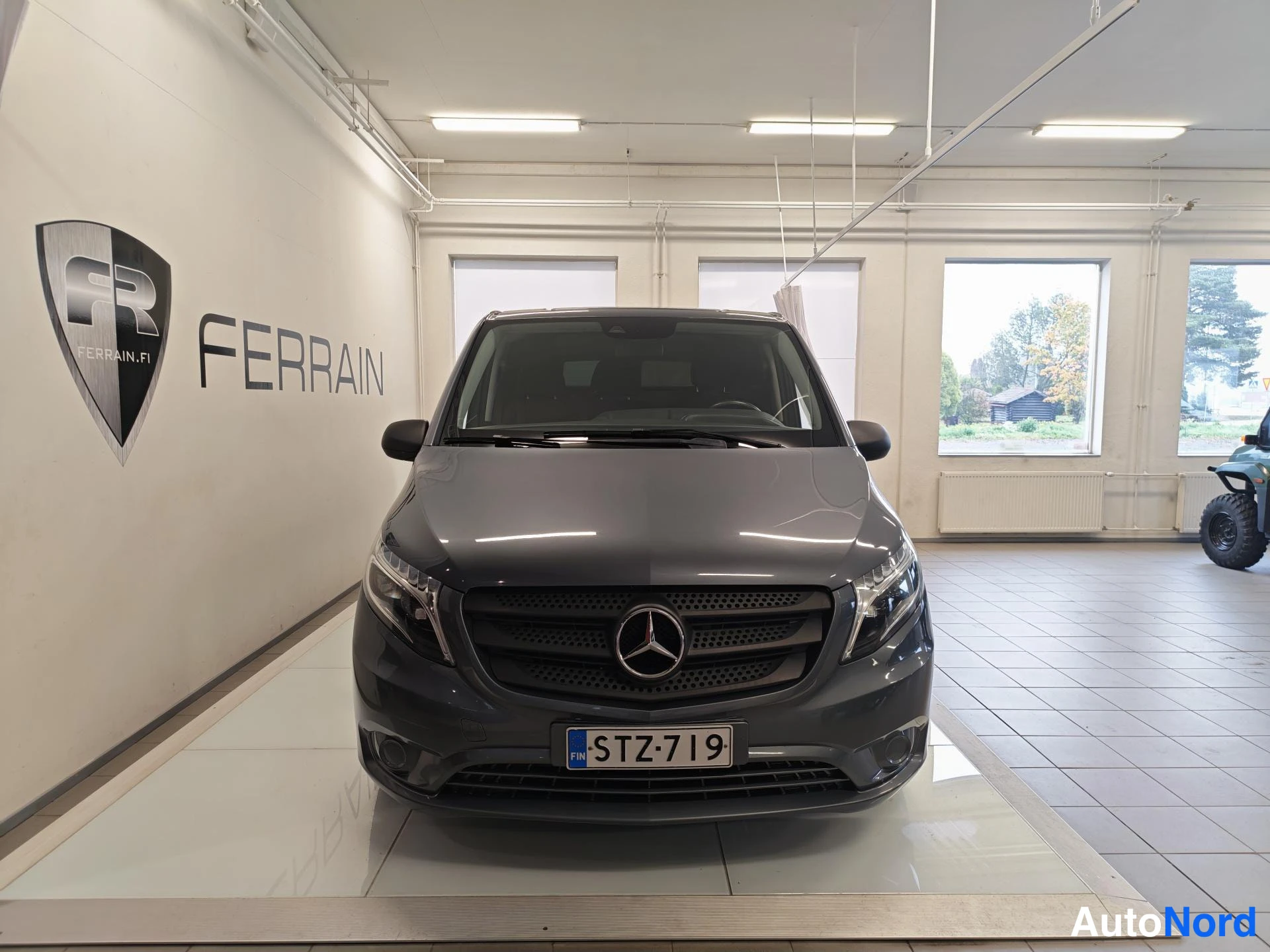Edestä: Mercedes-Benz Vito -pakettiauto suoraan edestä kuvattuna sisätiloissa, rekisterikilpi.