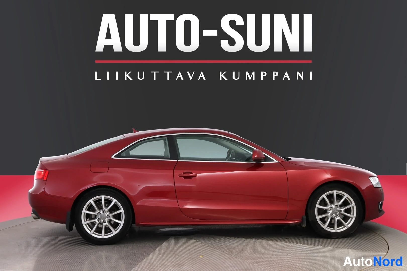 Takaviisto: Punaisen Audi A5 -coupén sivuprofiili studio-taustaa vasten, AUTO-SUNI-logoteksti kuvan yläosassa.