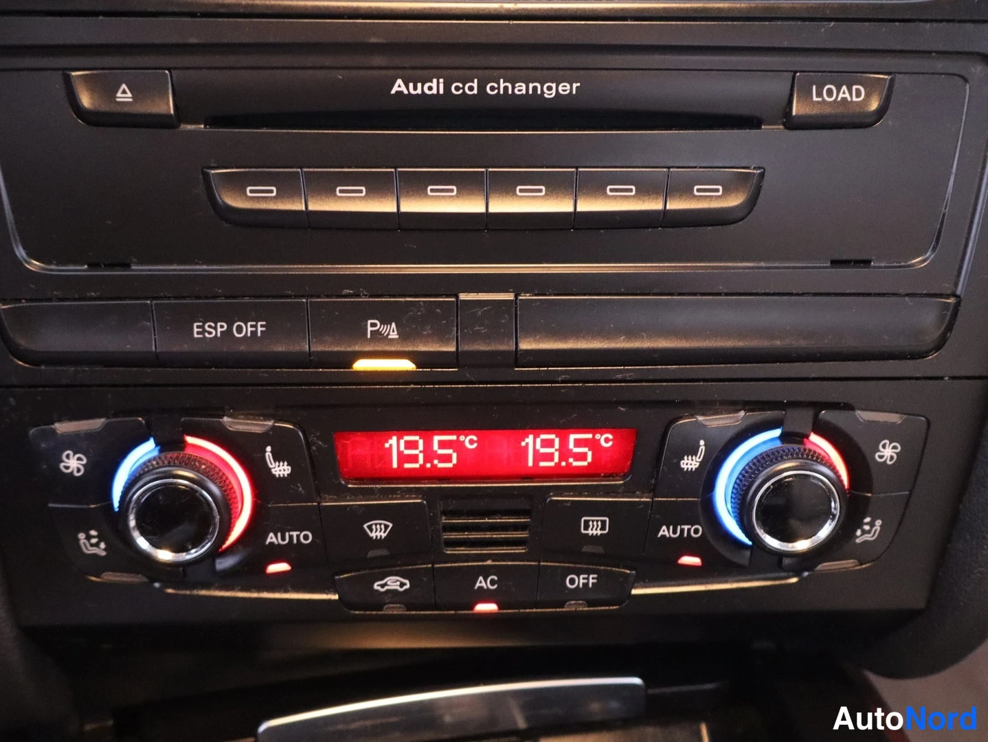 Muu: Keskinäytön valokuva: Audi cd changer -laite, ESP OFF- ja parkkiapunappi sekä automaattinen klimaanati, jonka näyttö näyttää 19,5 °C molemmin puolin.