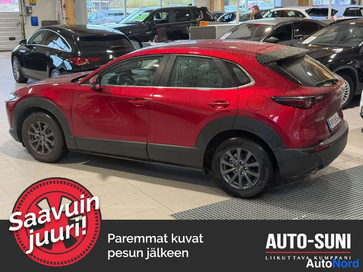 Takaviisto: Punainen Mazda CX-30 takakolmasosan kuvassa autosalonissa, rekisterikilpi näkyvissä takana.